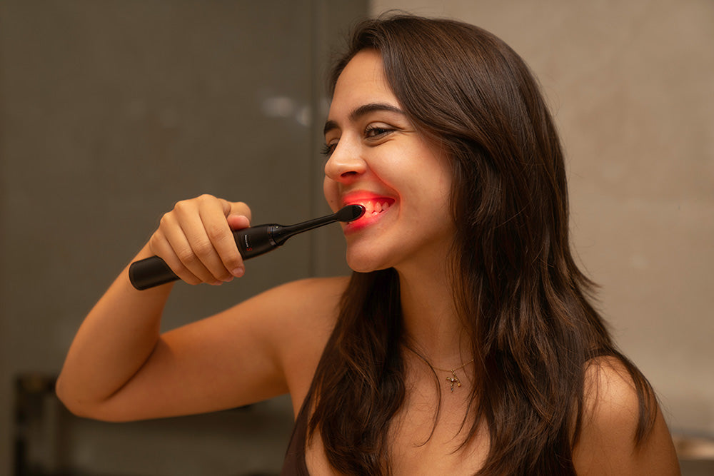 Woman brushing her teeth in front of a mirror